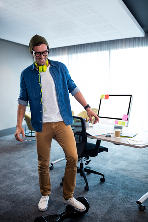 Hipster man using a smart balance wheel in the officeの写真素材