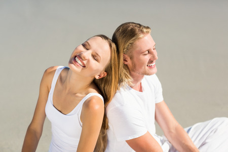 Happy young couple sitting on beach on a sunny dayの写真素材