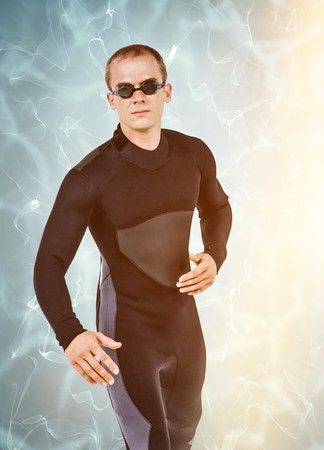 Swimmer in wetsuit and swimming goggles against blue pool under bright lightの写真素材