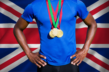 Portrait of athletic man chest holding gold medals against digitally generated uk national flagの写真素材