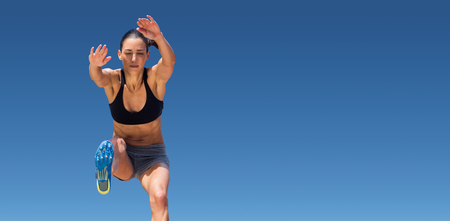 Sportswoman jumping on a white background against scenic view of blue skyの写真素材