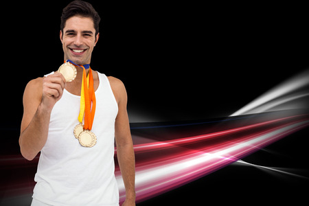 Athlete posing with gold medals around his neck against black backgroundの写真素材