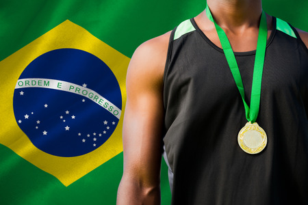 Portrait of sportsman chest with a medal  against digitally generated brazilian national flagの写真素材