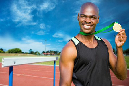 Athletic man posing with his gold medal against facing view of run tracksの写真素材