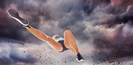 Low angle female athlete jumping against gloomy skyの写真素材