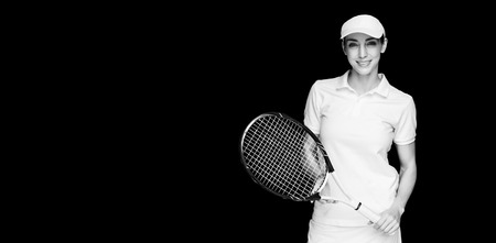 Female athlete posing with tennis racket on black backgroundの写真素材