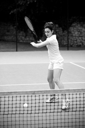 Pretty tennis player hitting ball on a sunny dayの写真素材