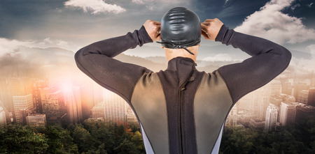 Rear view of swimmer in wetsuit wearing swimming goggles against trees and mountain range against cloudy skyの写真素材