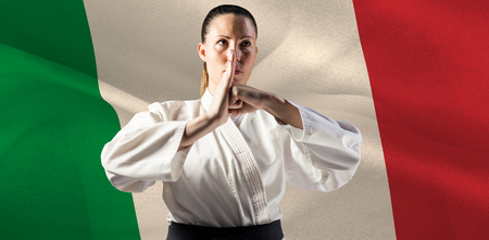 Female fighter performing hand salute against digitally generated italy national flagの写真素材