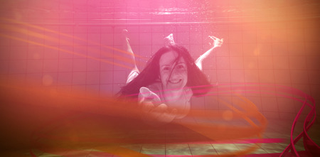 Pretty brunette smiling and offering her hand underwater in the swimming pool at the leisure centreの写真素材