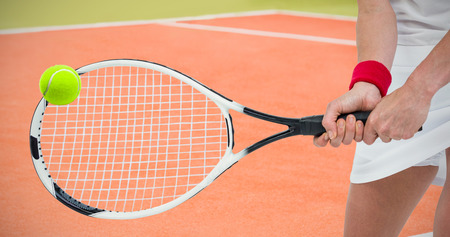 Athlete playing tennis with a racket  against composite image of tennis fieldの写真素材