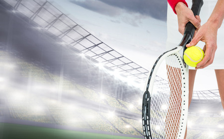 Athlete holding a tennis racquet ready to serve  against sports arenaの写真素材