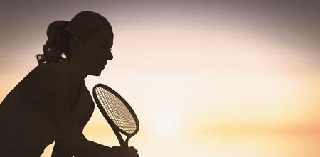Athlete playing tennis with a racket  against purple and orange skyの写真素材