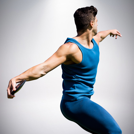 Side view of man throwing discus against grey backgroundの写真素材