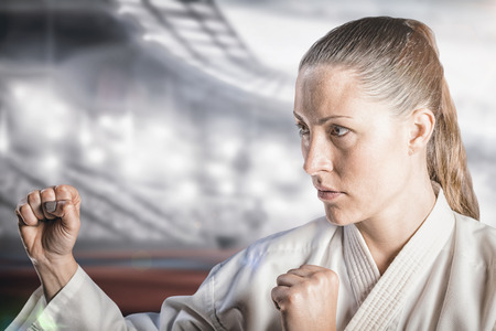 Female fighter performing karate stance against composite image of american stadiumの写真素材