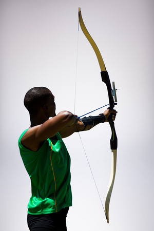 Rear view of sportsman doing archery on a white background against grey background