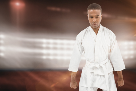 Front view of karate fighter meditating against composite image of playing field indoorの写真素材