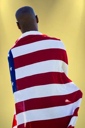 Rear view of man wearing american flag against yellow backgroundの写真素材