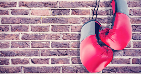 Boxing gloves attached to white background against image of a wallの写真素材