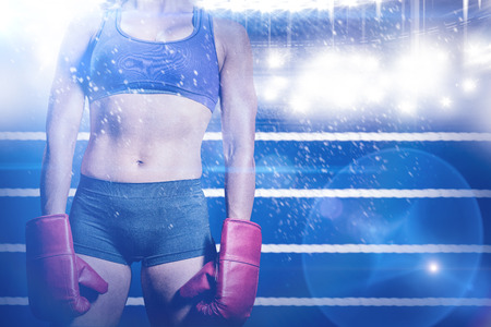 Midsection of female boxer with gloves against composite image of ring ropesの写真素材