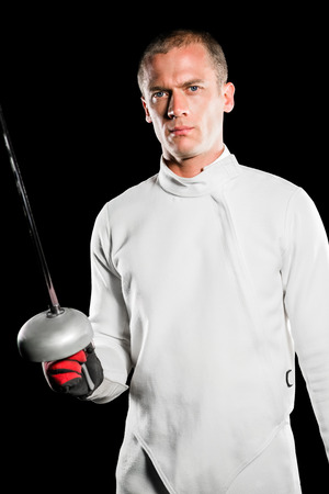 Portrait of swordsman holding fencing sword on black background