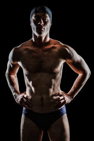 Portrait of swimmer standing with hand on hip on black backgroundの写真素材