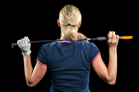 Rear view of golf player holding a golf club on black backgroundの写真素材