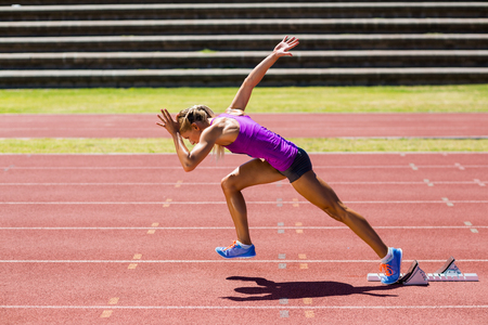 Female athlete running on the racing track on a sunny dayの写真素材