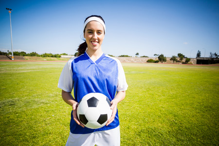 Happy soccer player standing in stadium with a ballの写真素材