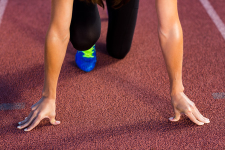 Female athlete in ready to run position on running track