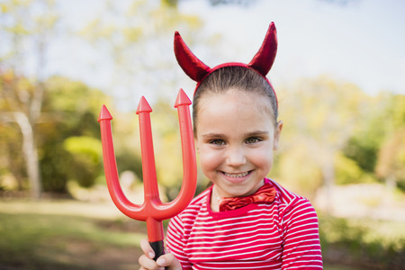 Adorable girl pretending to be a devil in the parkの写真素材