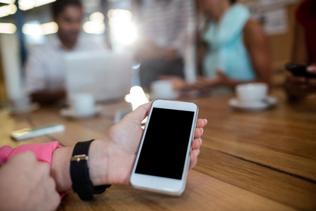 Casual businesswoman holding smartphone in the office