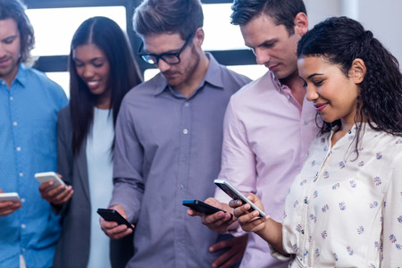Group of hipsters using a smartphone in the officeの写真素材