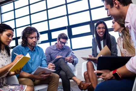 Group of coworkers with folders interacting in the officeの写真素材