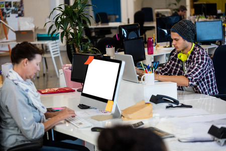 Coworkers typing on their computer in the open space