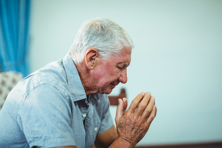 Worried senior man sitting in living room at homeの写真素材