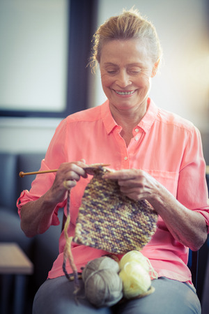 Senior woman knitting wool at homeの写真素材