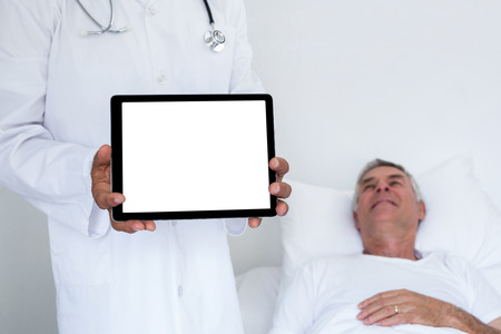 Doctor standing next to the patient and holding a digital tabletの写真素材