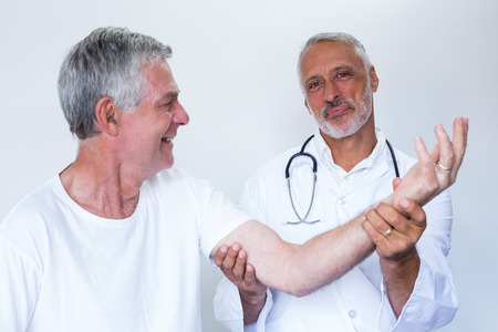 Male doctor giving palm acupressure treatment to senior man in hospitalの写真素材