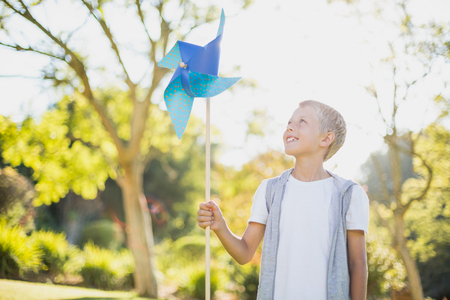 Boy holding a pinwheel and smiling in parkの写真素材