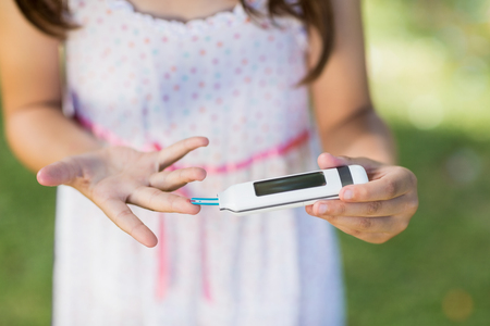 Close-up of girl testing diabetes on glucose meter in parkの写真素材