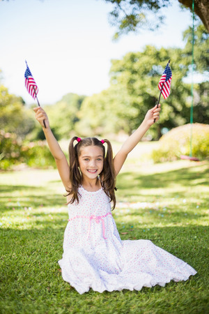 Cute girl holding American flags in parkの写真素材