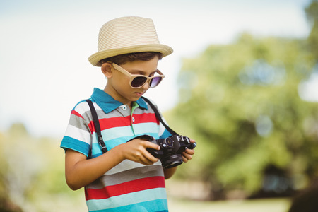 Young boy checking a photograph in camera at parkの写真素材