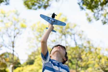 Boy playing with a toy aeroplane in parkの写真素材