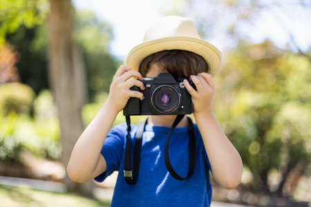 Young boy clicking a photograph from camera in parkの写真素材