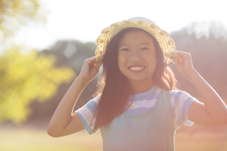 Portrait of young girl wearing hat smiling in park on a sunny dayの写真素材