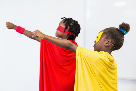 Boy and girl with hands raised pretending to be a superheroの写真素材