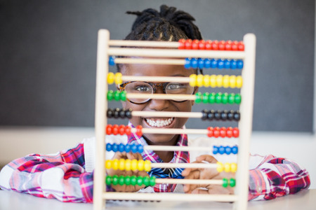 Portrait of smiling schoolgirl using a maths abacus at school