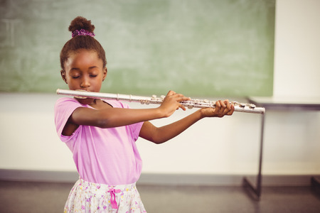 Schoolgirl playing flute in classroom at schoolの写真素材