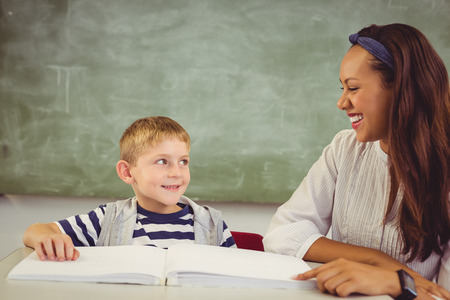 Teacher helping a boy with his homework in classroom at schoolの写真素材